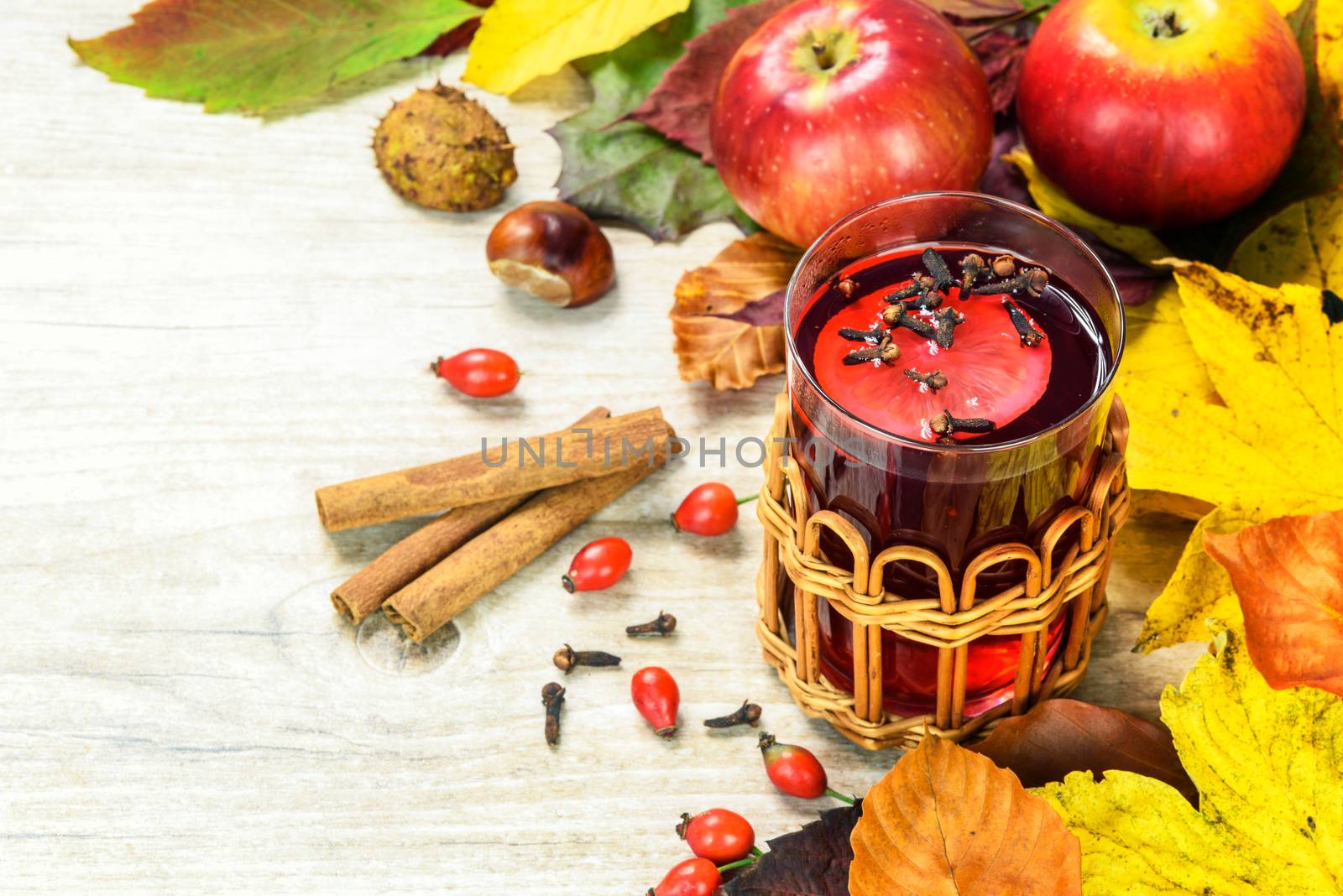 Concept of seasonal warm tea with wild rose, spices, lemons and surrounded by autumn rustic decoration.