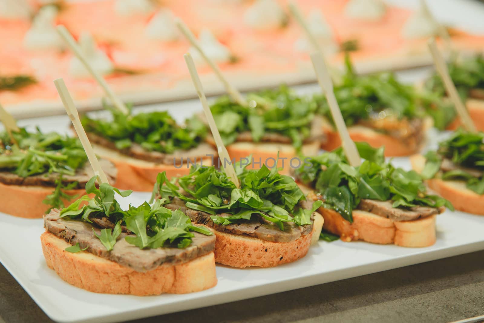 a plate of sandwiches and stuffing on a toothpick baguette, beef and lettuce.