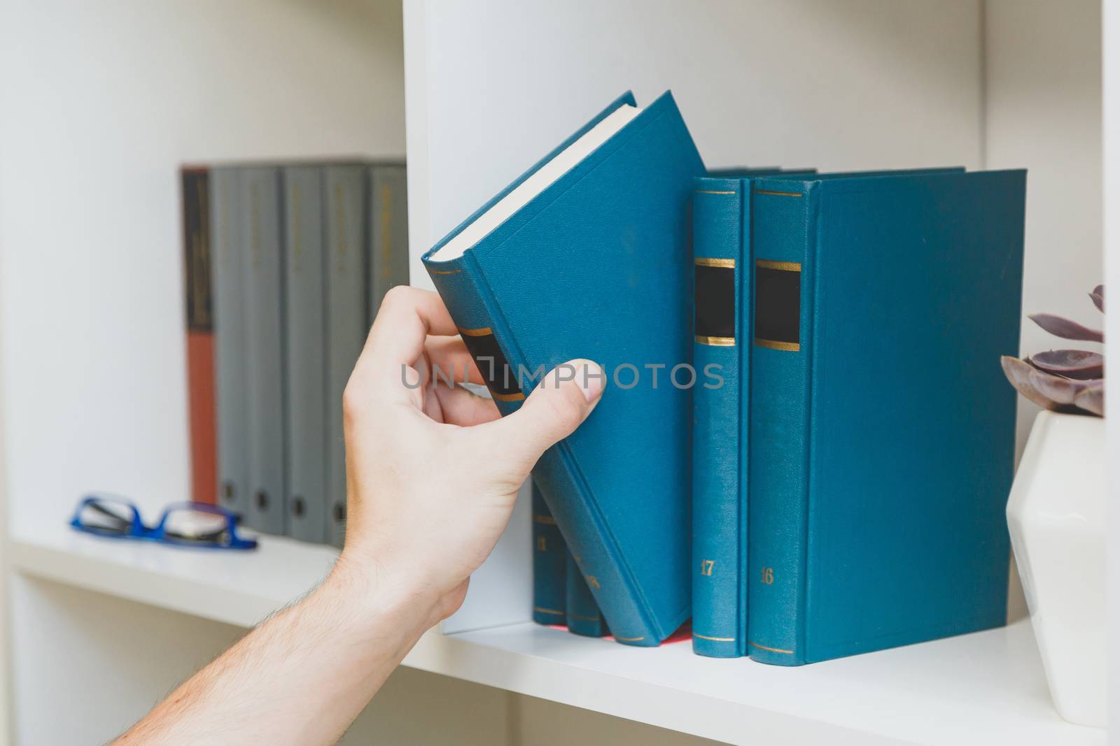 Hand taking book from the shelf by vladdeep