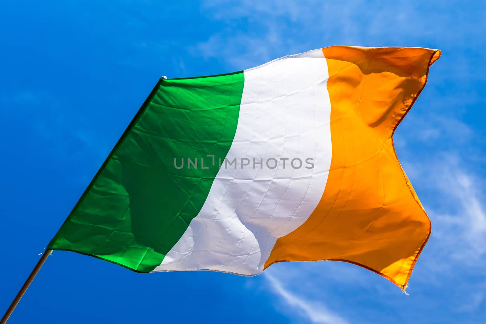 Irish flag fluttering in a brisk breeze against a bright blue sk by SeuMelhorClick