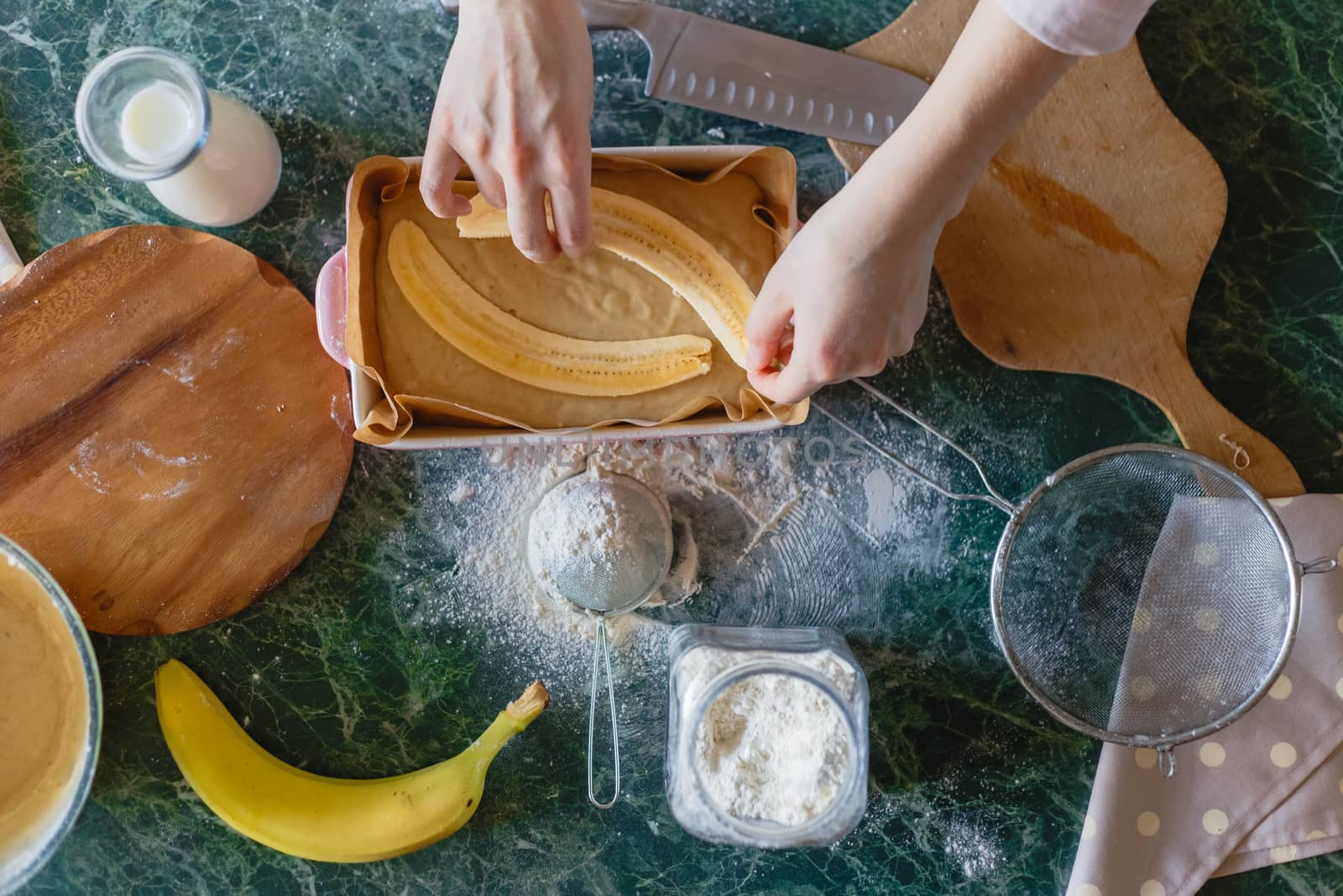 The girl puts the cut banana for the filling into the pie dough. Top view