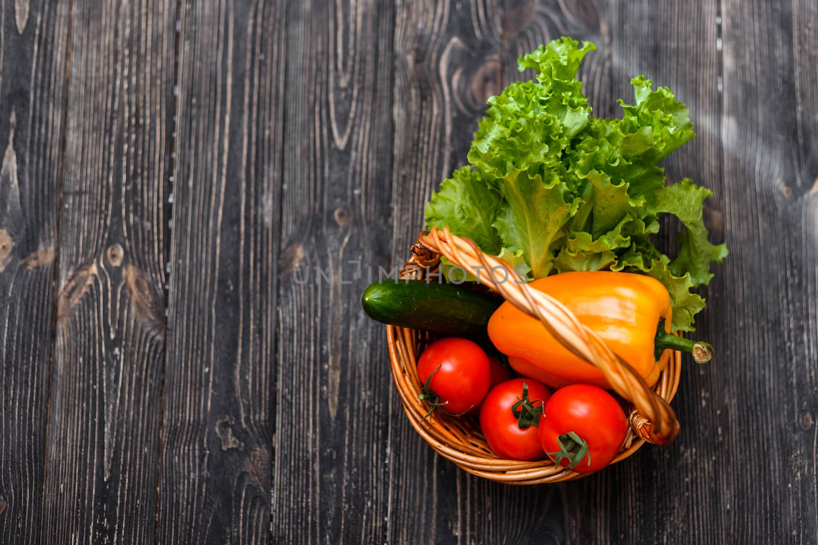 Basket with fresh vegetables on a rustic table. View from above.