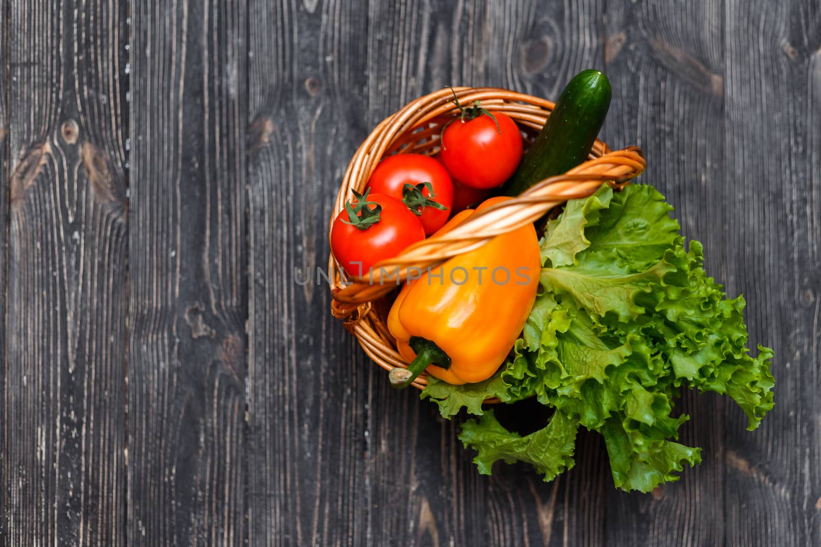 Basket with fresh vegetables on a rustic table. View from above