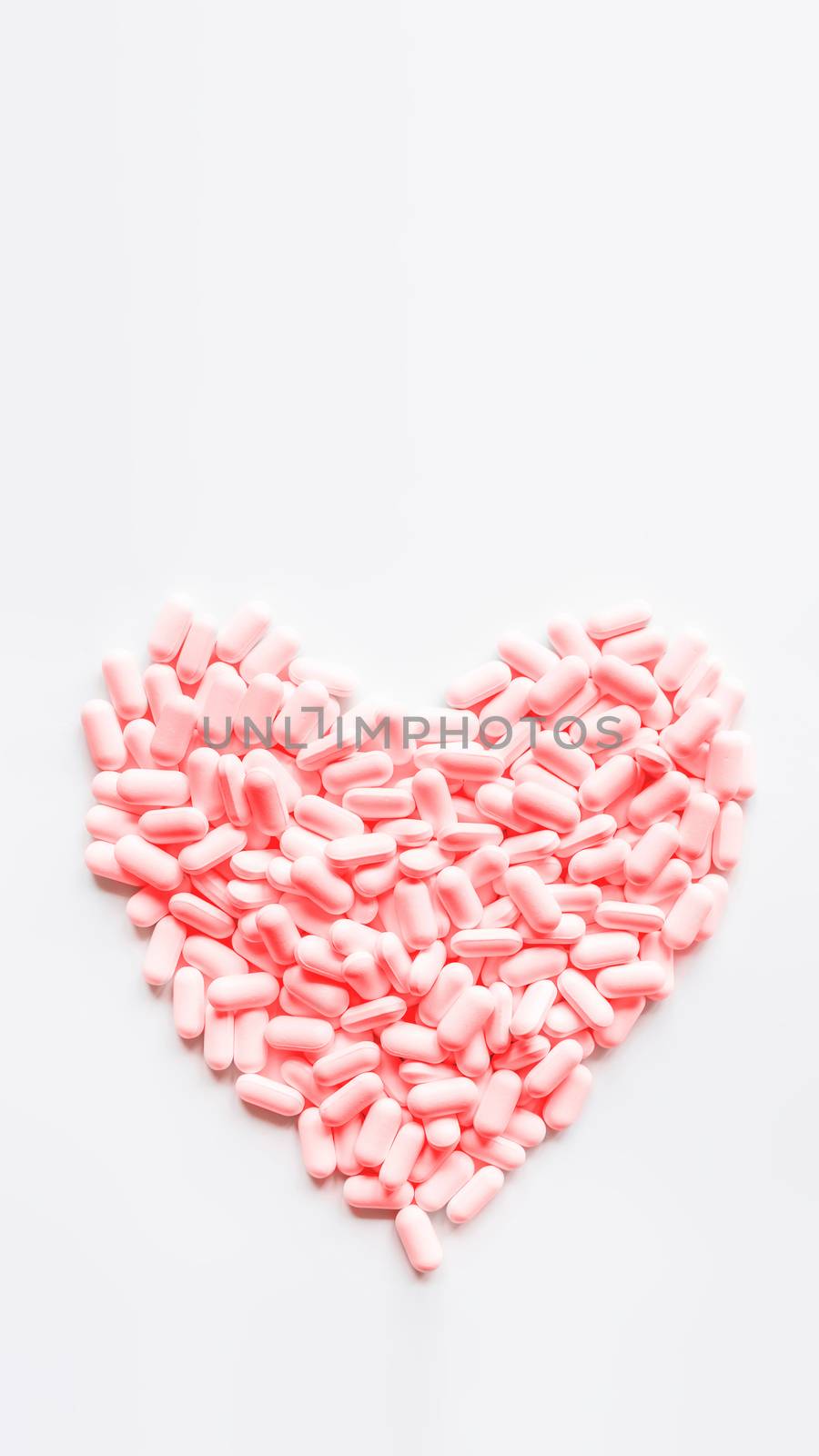 Heart made of pink pills. Top view on drugs in shape of heart. Flat lay white background with copy space.