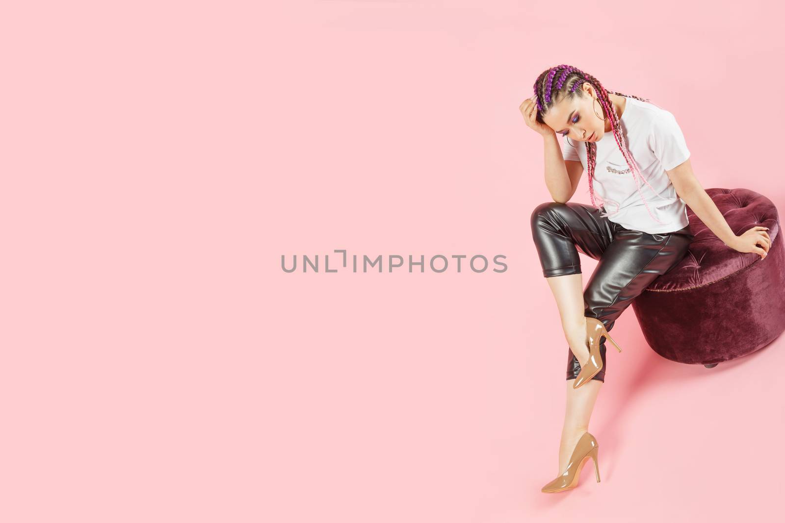 Fashionable brunette woman with canecalons in leather pants and white t-shirt, high heels shoes. Isolated on pink with copyspace. Fashion Photo