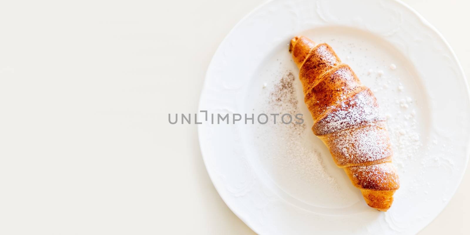 Continental breakfast background - croissant on plate. White table with copy space. Top view.