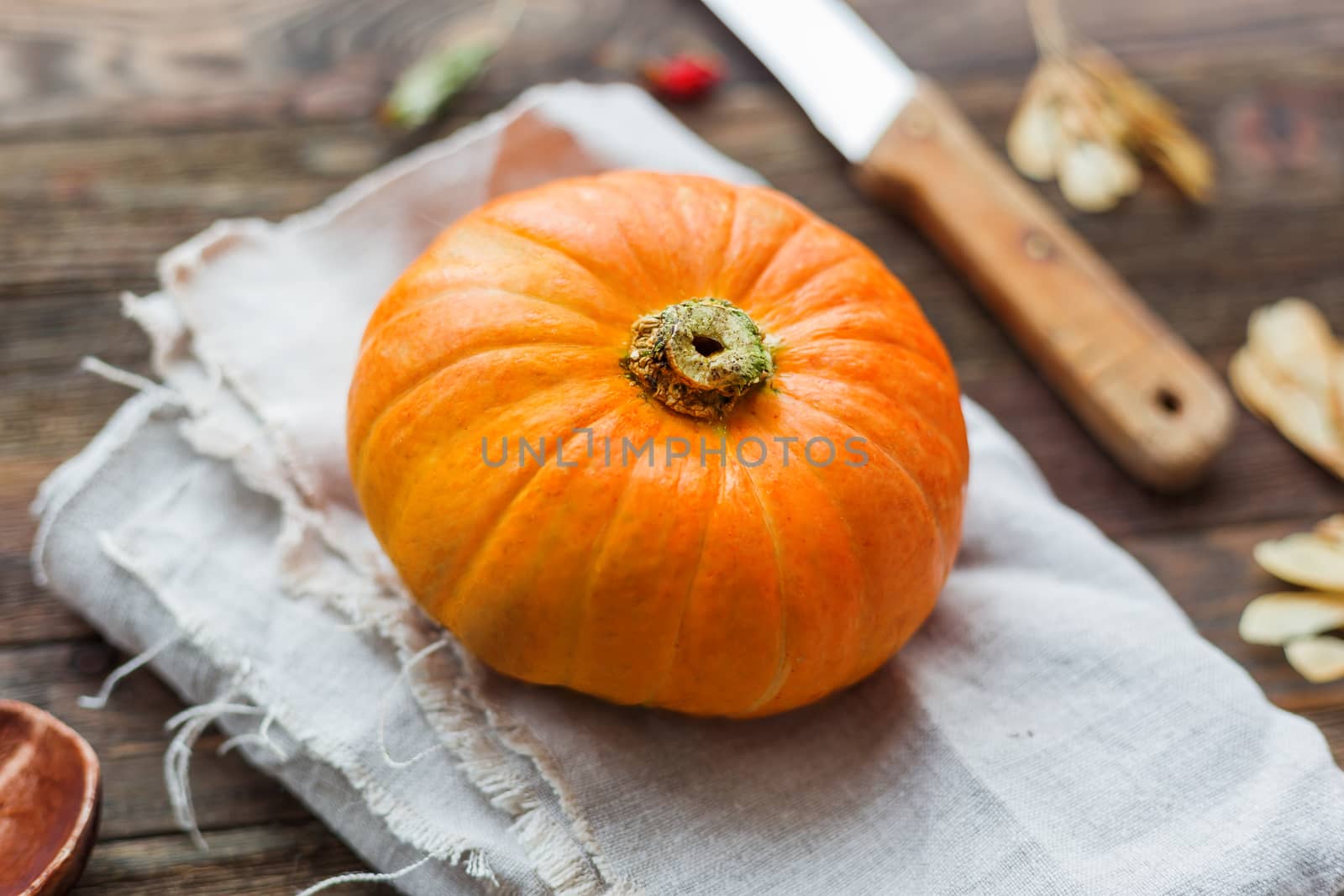 Fresh orange pumpkin on wooden table. Homespun napkin and rustic cutlery on background.