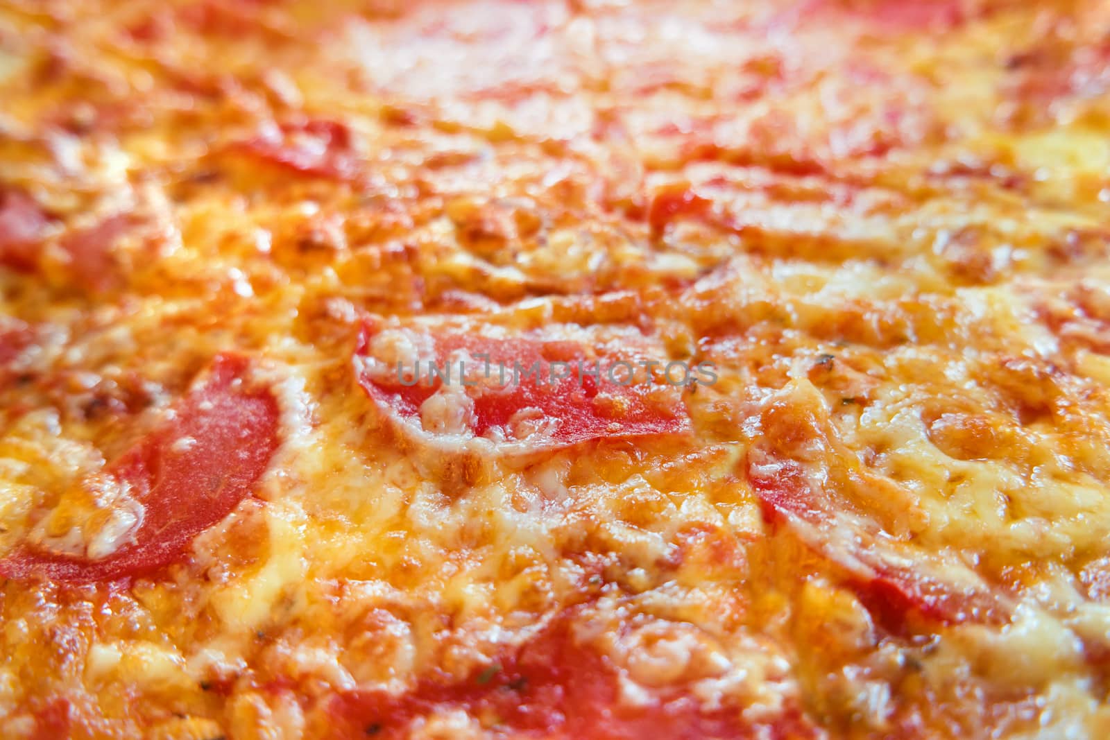 Close up photo of pizza. Macro photo of baked pizza ingredients - cheese with ham and tomatoes. Traditional italian cuisine.