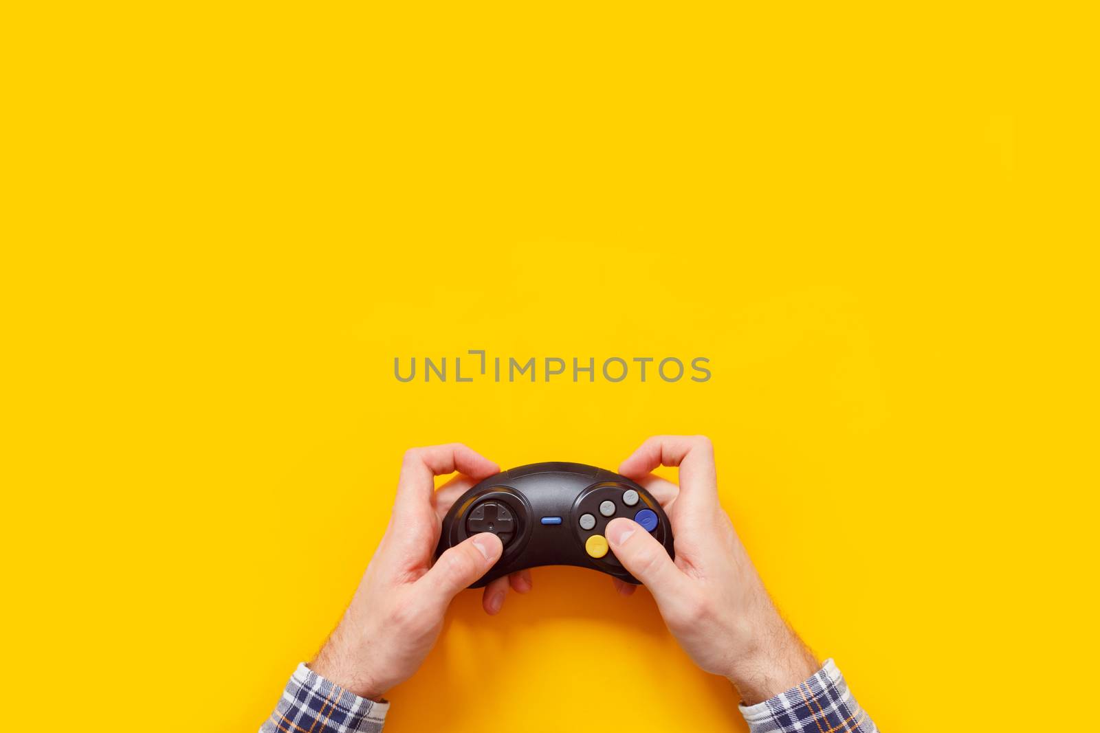 Man's hands with wireless gamepad isolated on yellow