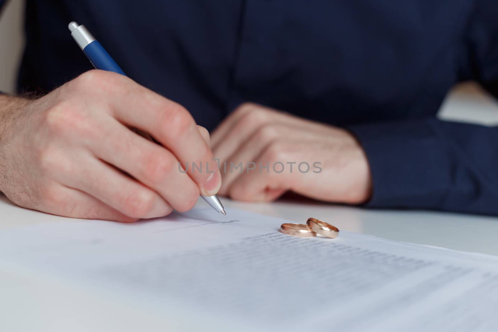 husband signing divorce agreement and woman push away weeding ring