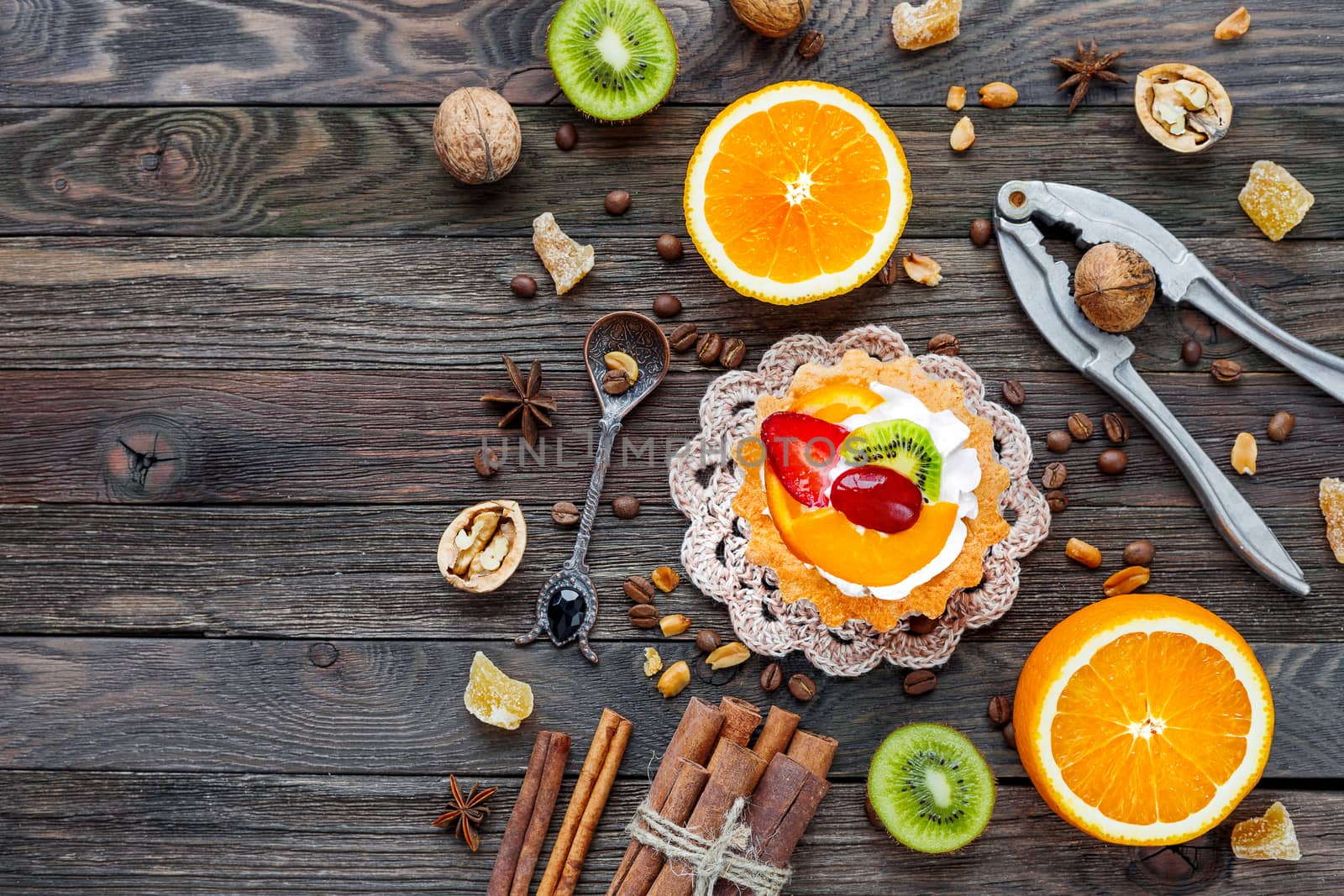 Rustic wooden background with fruit tart, spices, kiwi and oranges. Top view, flat lay. Place for text.