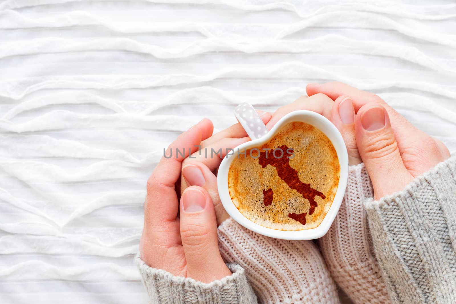 Woman and man holds a cup of hot coffee with cinnamon silhouette of Italy. Winter wanderlust and Valentine's Day fabric background.