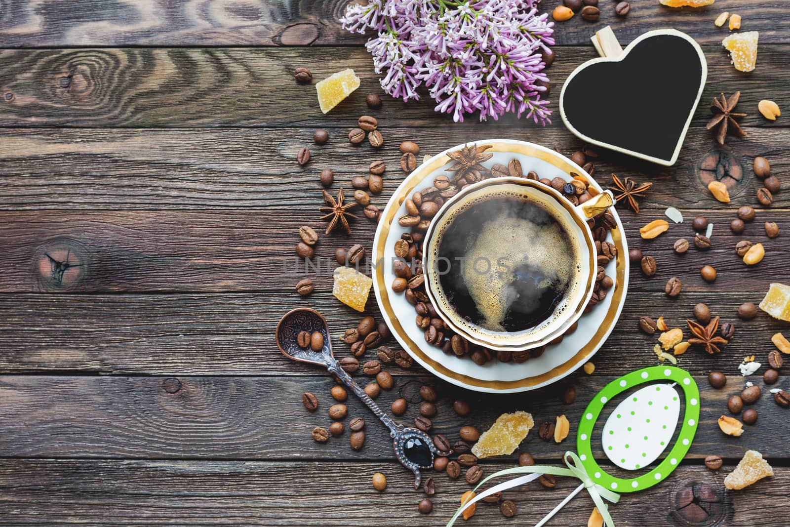 Rustic wooden background with cup of coffee and Easter decorations. Hot beverage with heart chalkboard. Top view, place for text.
