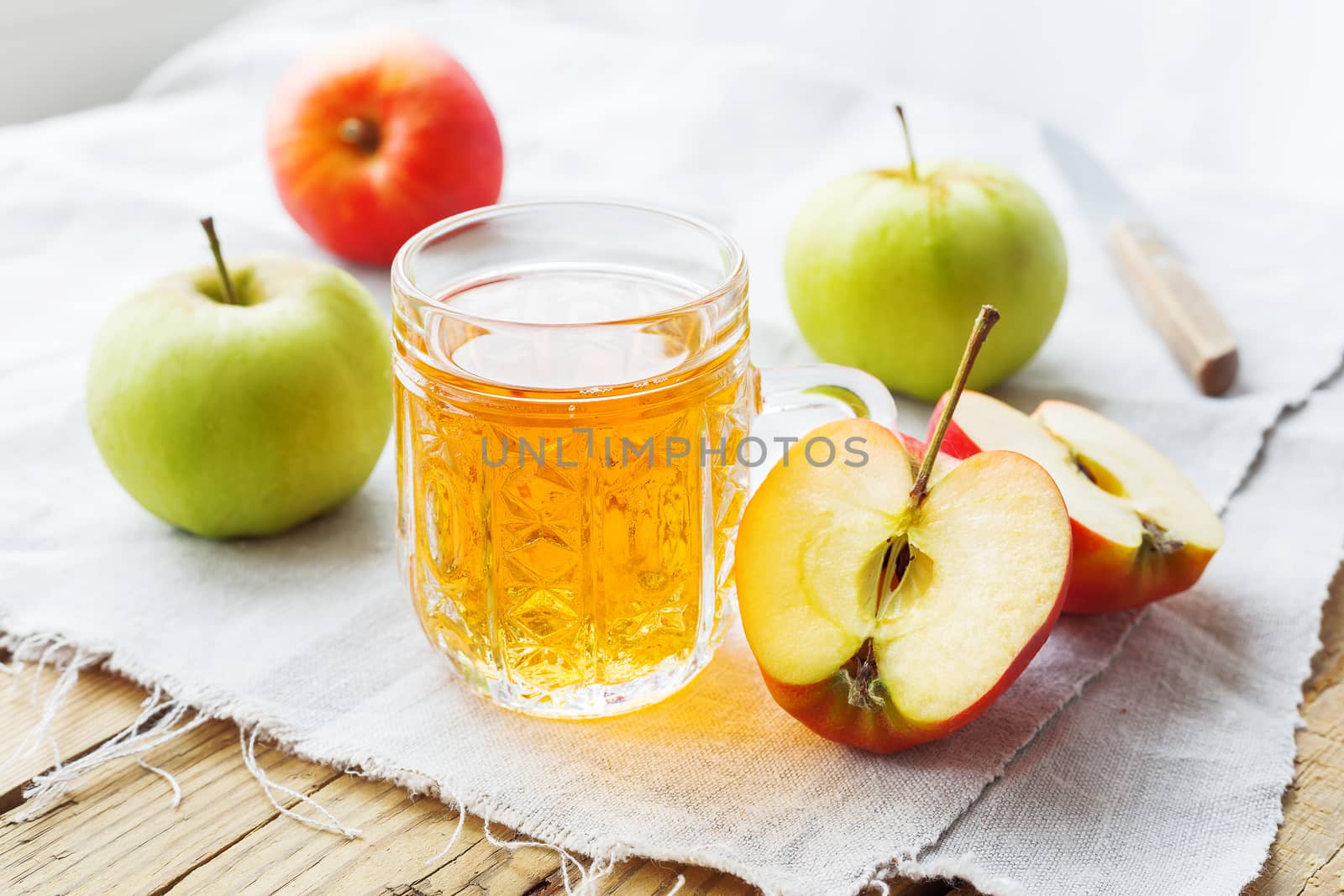 Rustic background with apples and apple juice in glass on homespun napkin.
