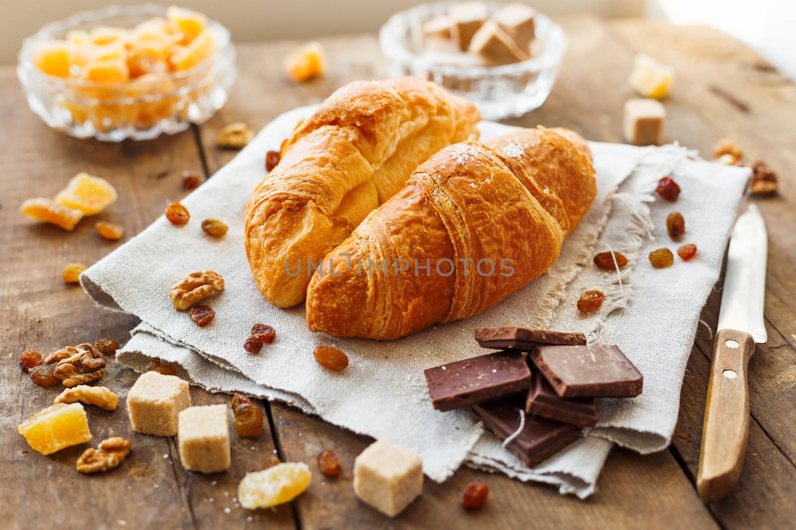Breakfast background - pair of croissants with chocolate, sugar, ginger and walnuts on rustic wooden background.