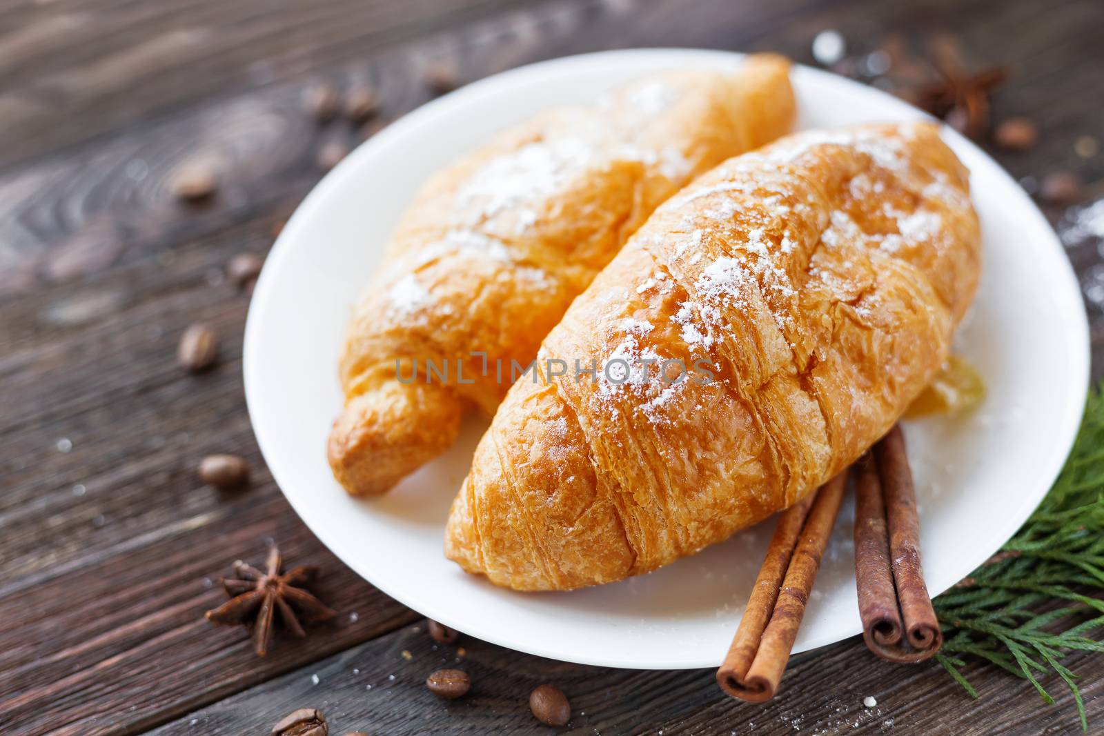 Continental breakfast background - pair of croissants with cinnamon. Rustic wooden background.