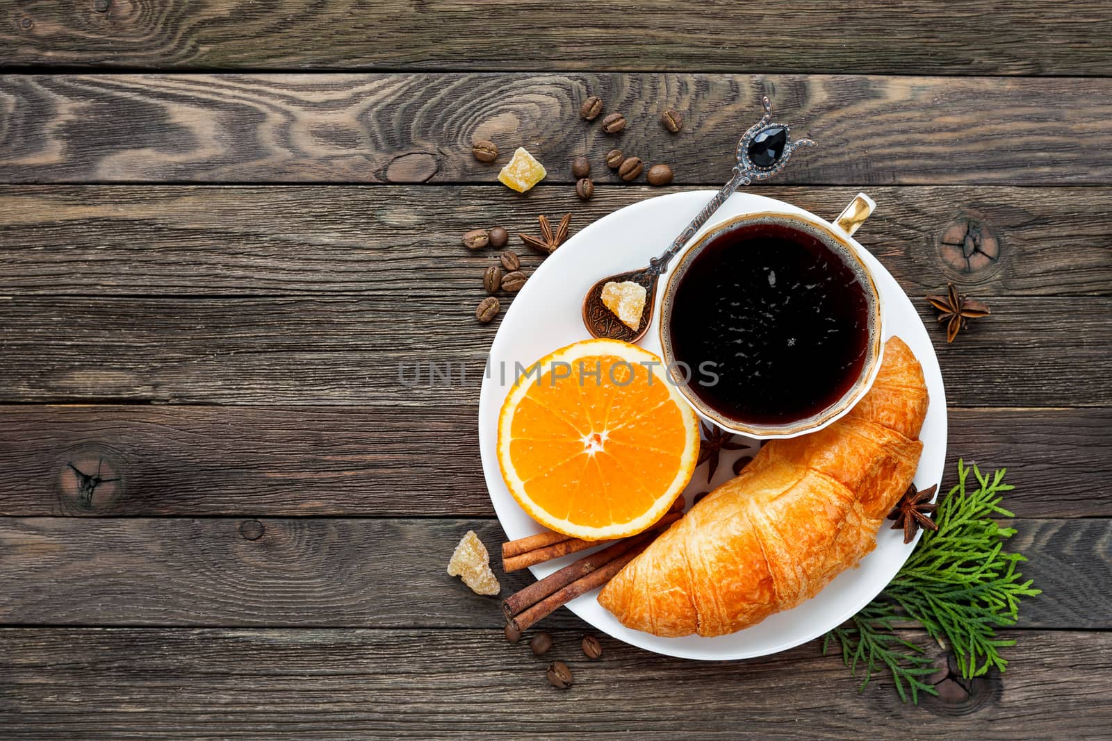 Continental breakfast - cup of hot coffee, croissant and orange. Tasty food on rustic wooden background. Top view, place for text.