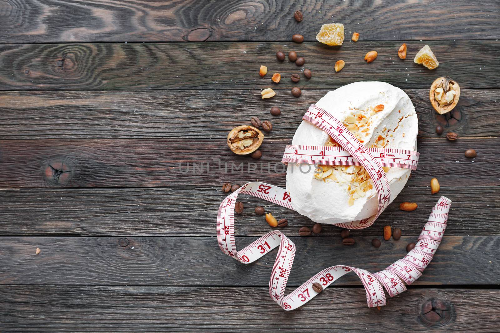 Rustic wooden background with meringue and tailor's ruler. Diet concept. Unhealthy eating. Top view, place for text.