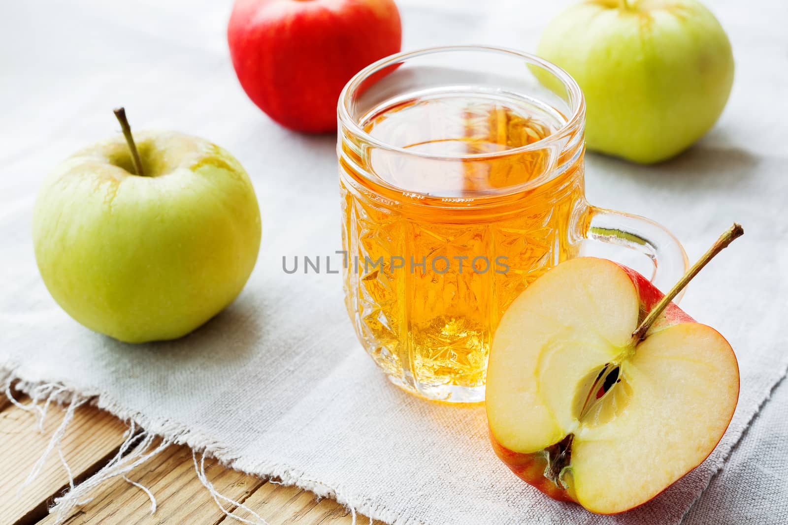 Rustic background with apples and apple juice in glass on homespun napkin.