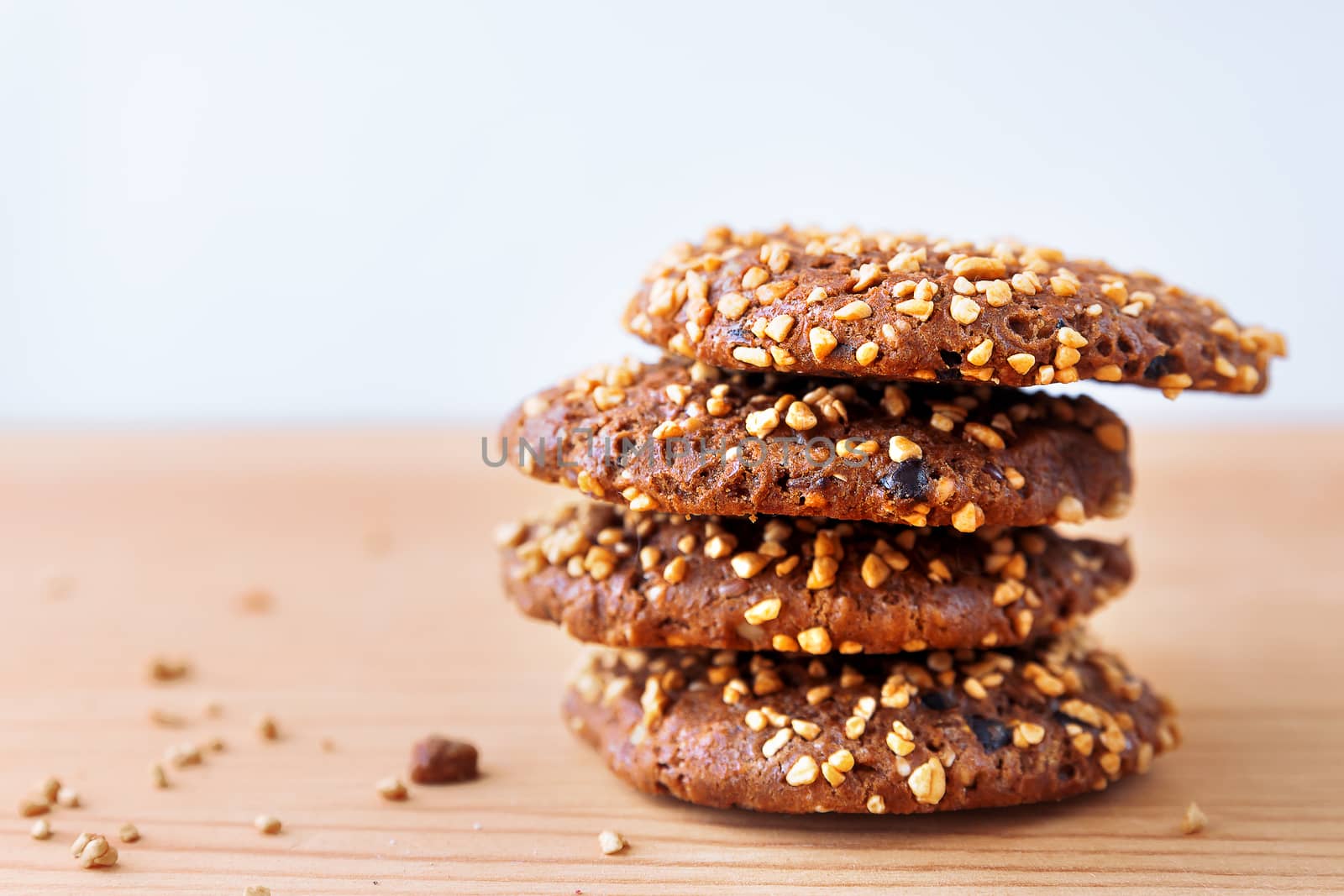 Oat cookies with nuts, sesame and chocolate on wooden background.