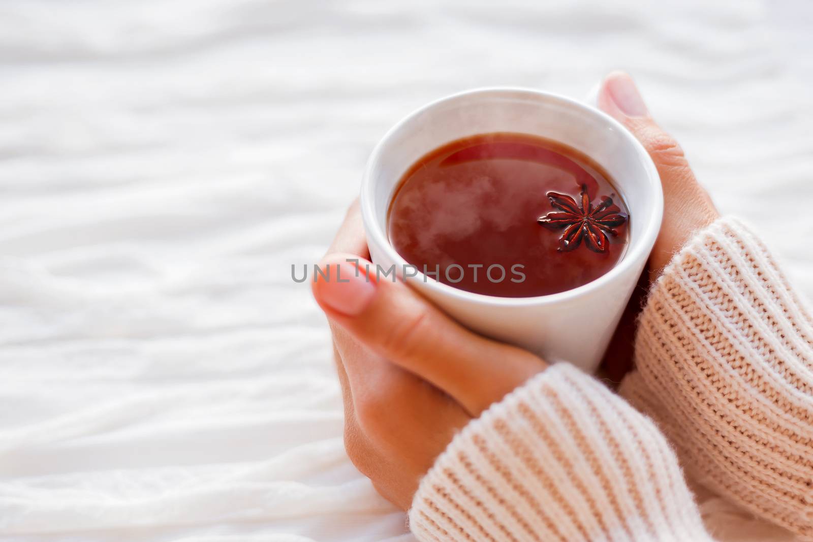 Women holds a cup of hot tea with anise star. Cozy morning at home.