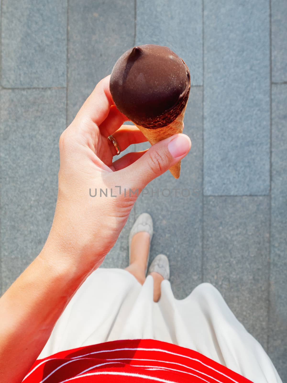 Woman in red shirt and skirt is holding ice-cream. Top view on cold dessert. Summer fun.