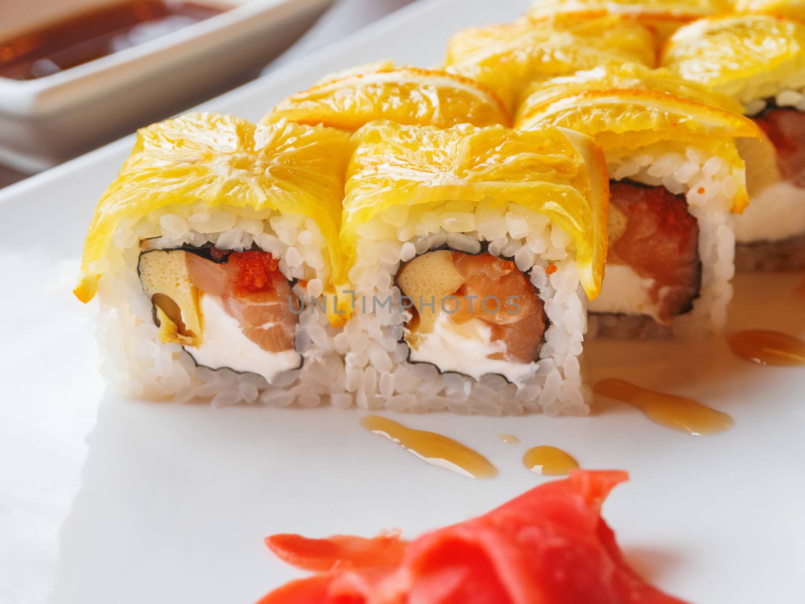 Rolls with rice, seaweed nori, salmon, cream cheese, chicken egg, caviar masago, orange. Marinated ginger and wasabi sauce. Asian cuisine, traditional dish - sushi.