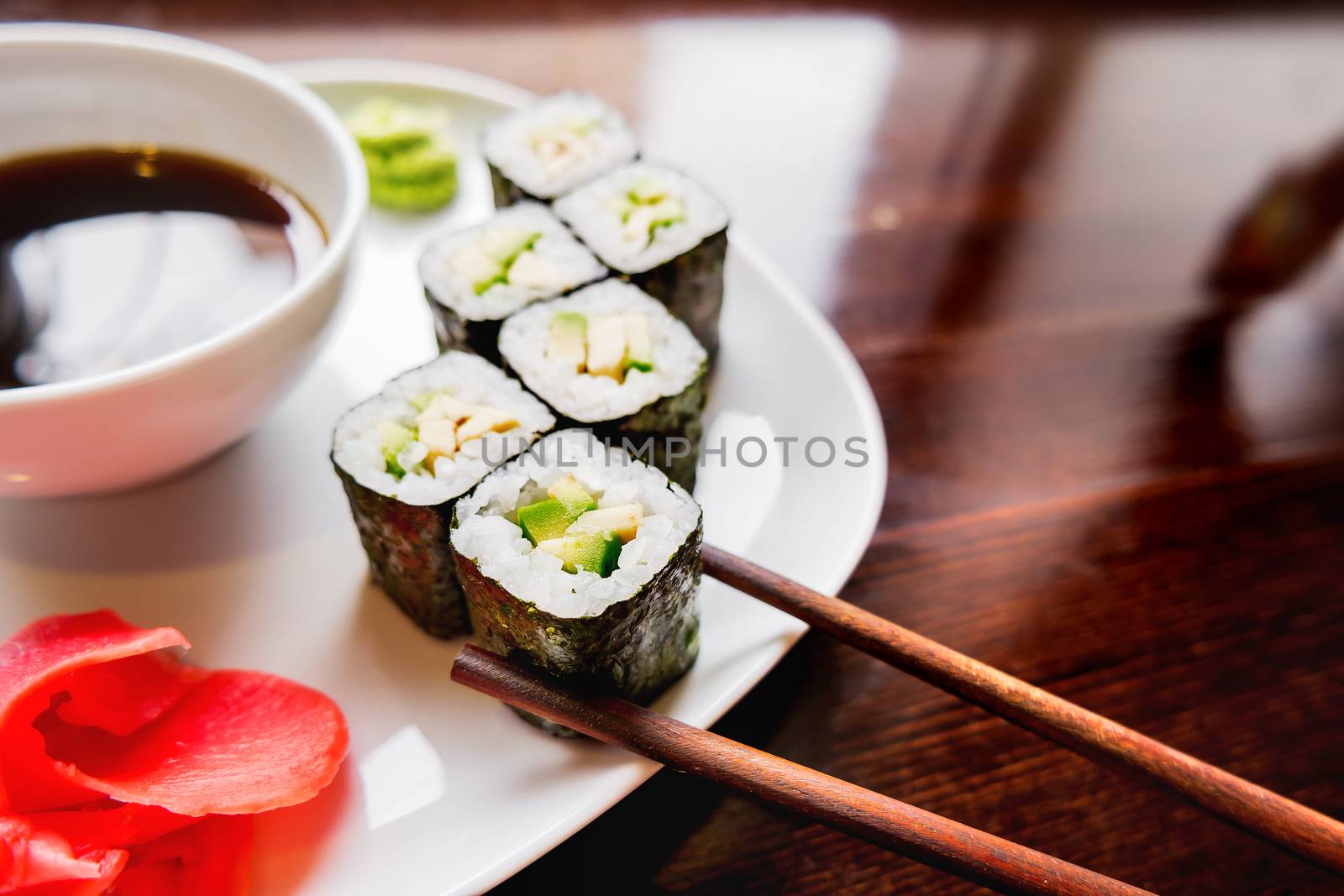 Rolls in nori seaweed with avocado, pickled ginger and soy sauce. Asian cuisine, traditional dish - sushi.