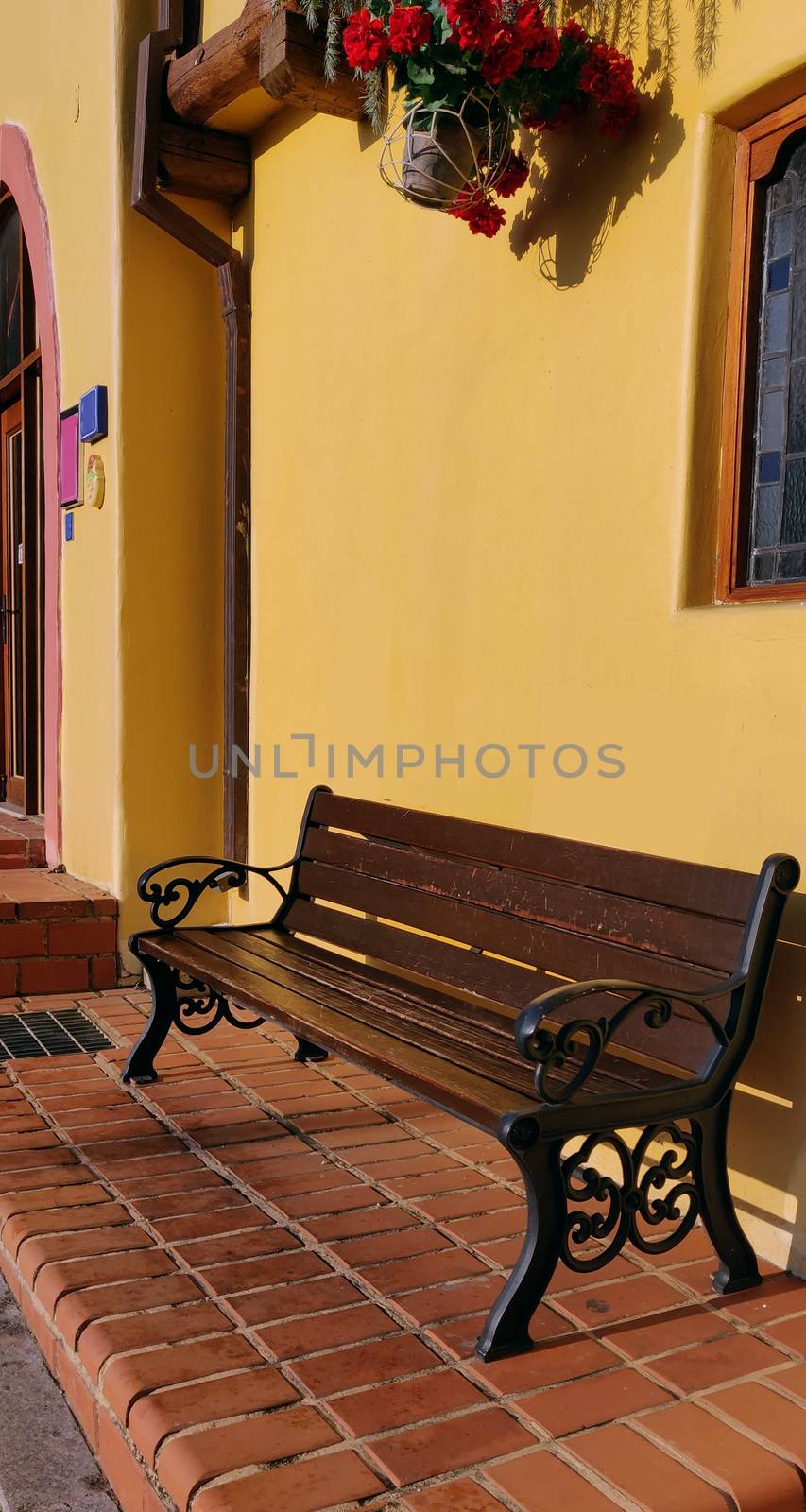 A wooden bench in a street with yellow walls by mshivangi92