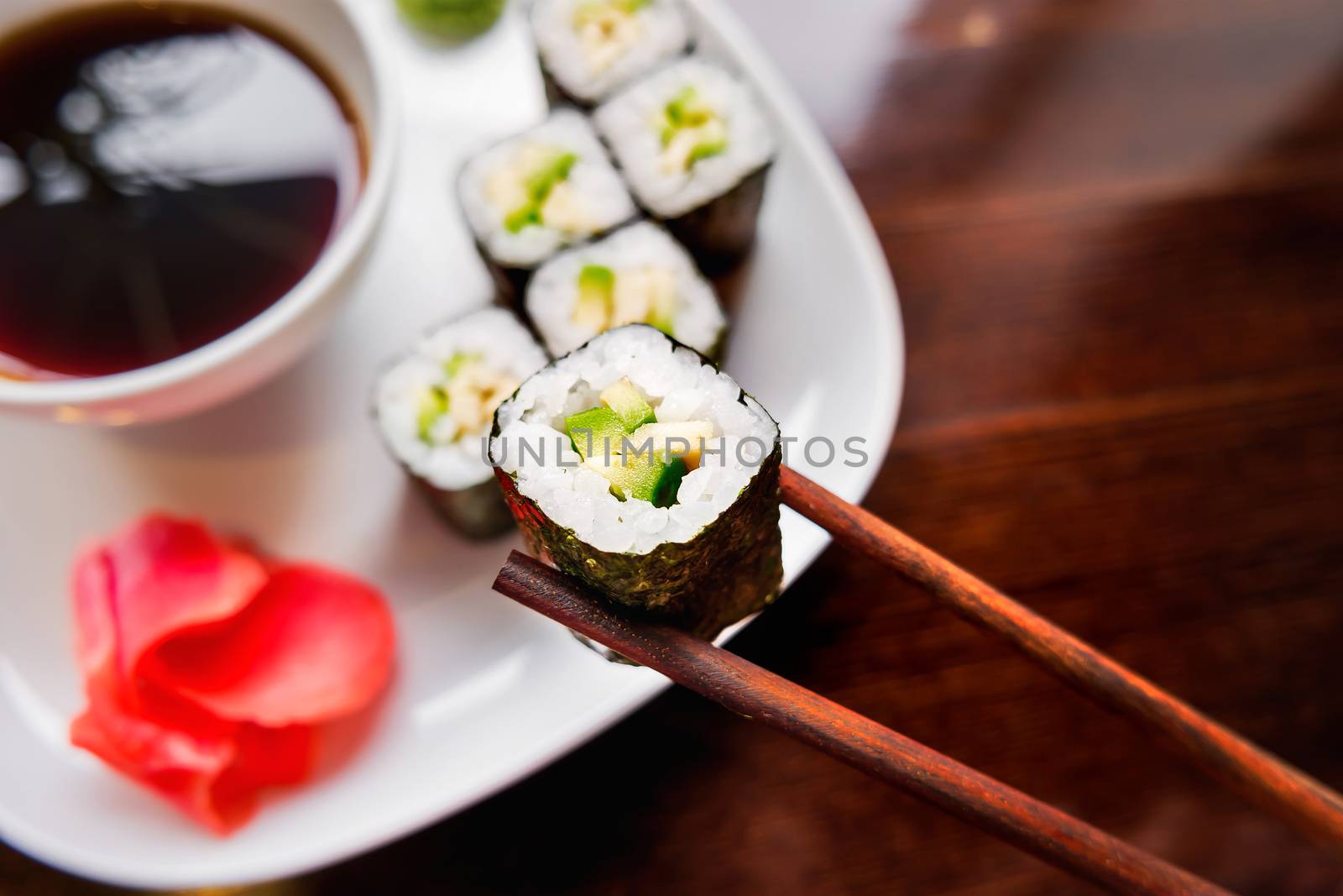 Rolls in nori seaweed with avocado, pickled ginger and soy sauce. Asian cuisine, traditional dish - sushi.