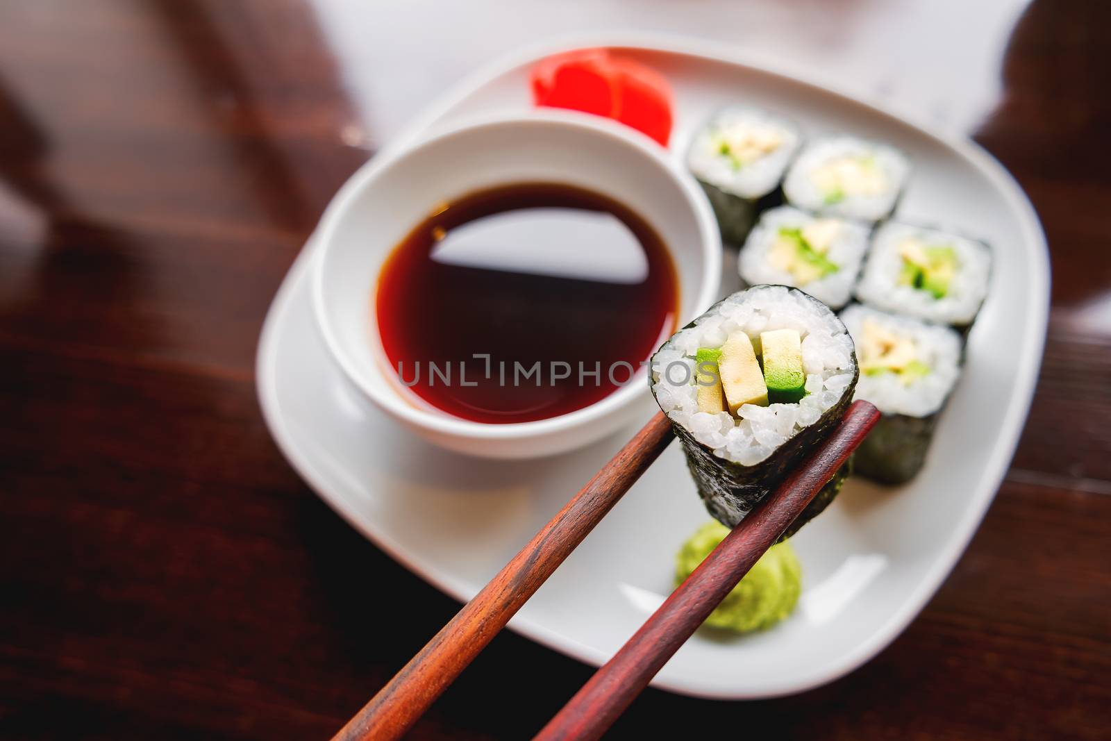 Rolls in nori seaweed with avocado, pickled ginger and soy sauce. Asian cuisine, traditional dish - sushi.