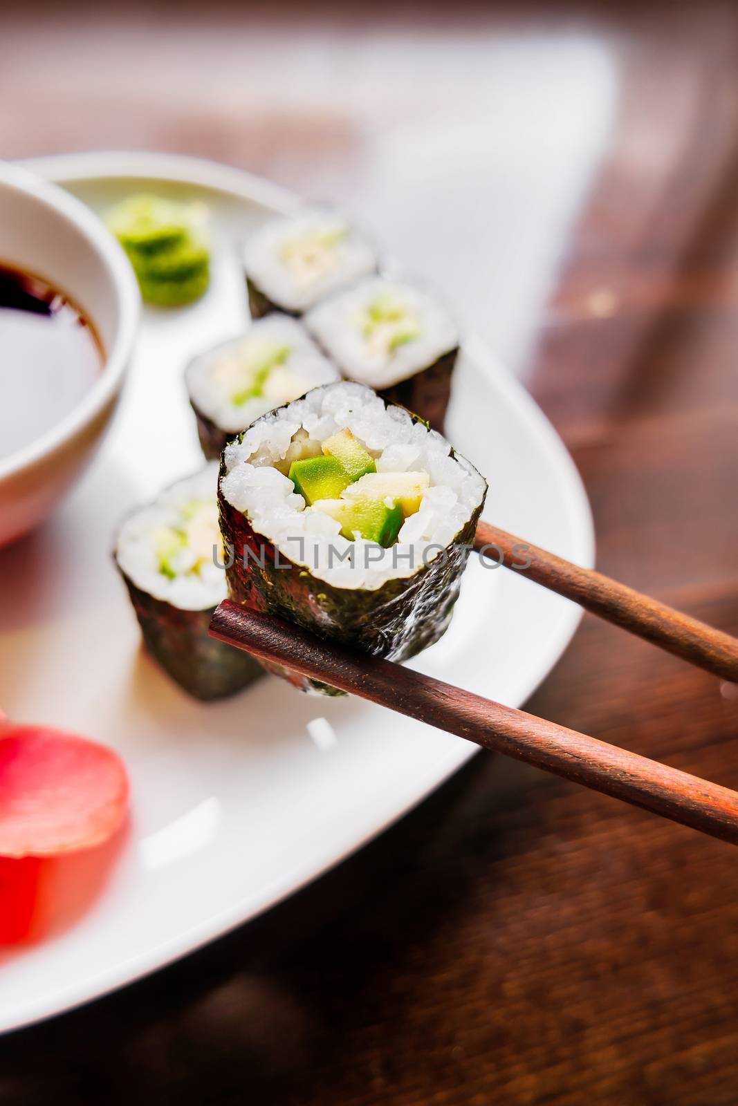 Rolls in nori seaweed with avocado, pickled ginger and soy sauce. Asian cuisine, traditional dish - sushi.