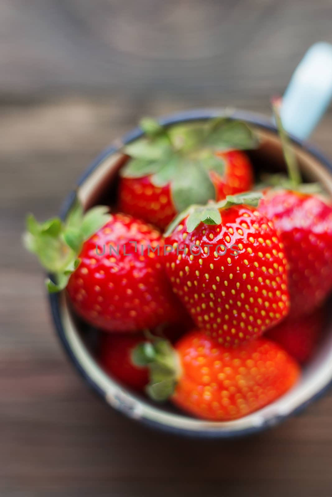 Fresh juicy strawberries in old rusty mug. Rustic wooden background. Top view, place for text.