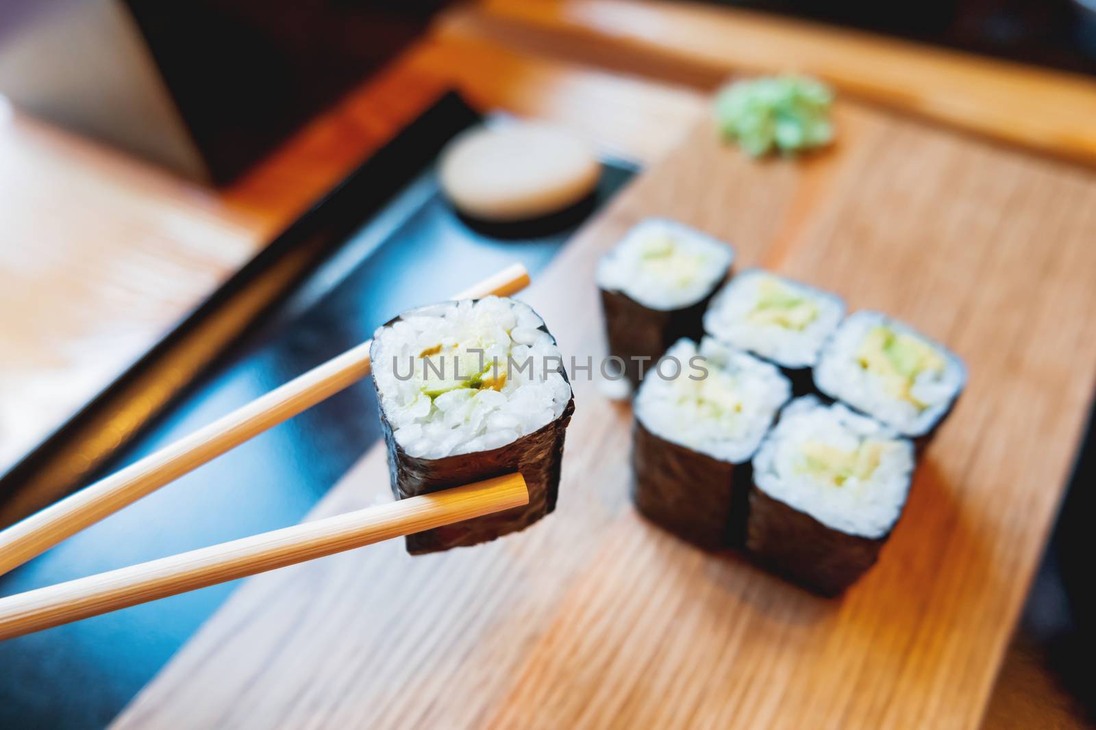 Rolls in nori seaweed with avocado, pickled ginger and soy sauce. Asian cuisine, traditional dish - sushi.