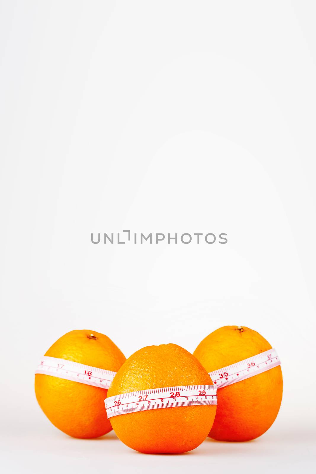 Three oranges with tailor's ruler. Orange diet. Fruit healhy vitamin diet helps to lose weight. Place for text.