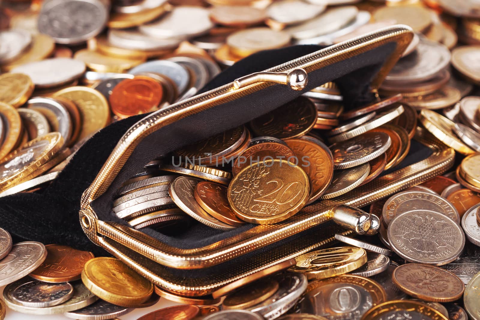 Black wallet with different coins. Big heap of shiny coins as background.
