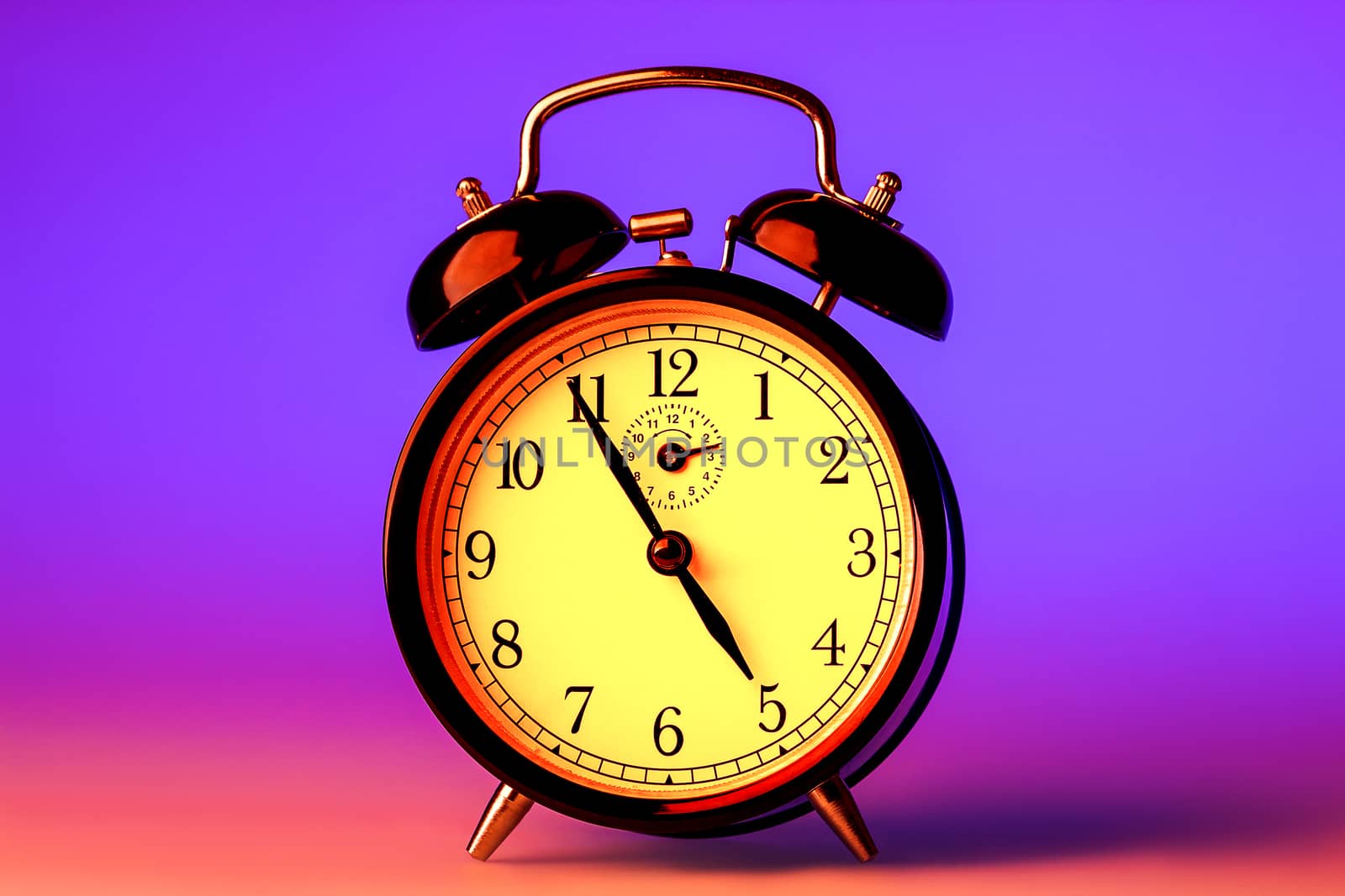 Black old fashioned alarm clock in disco lights. Time to have a party and dance.
