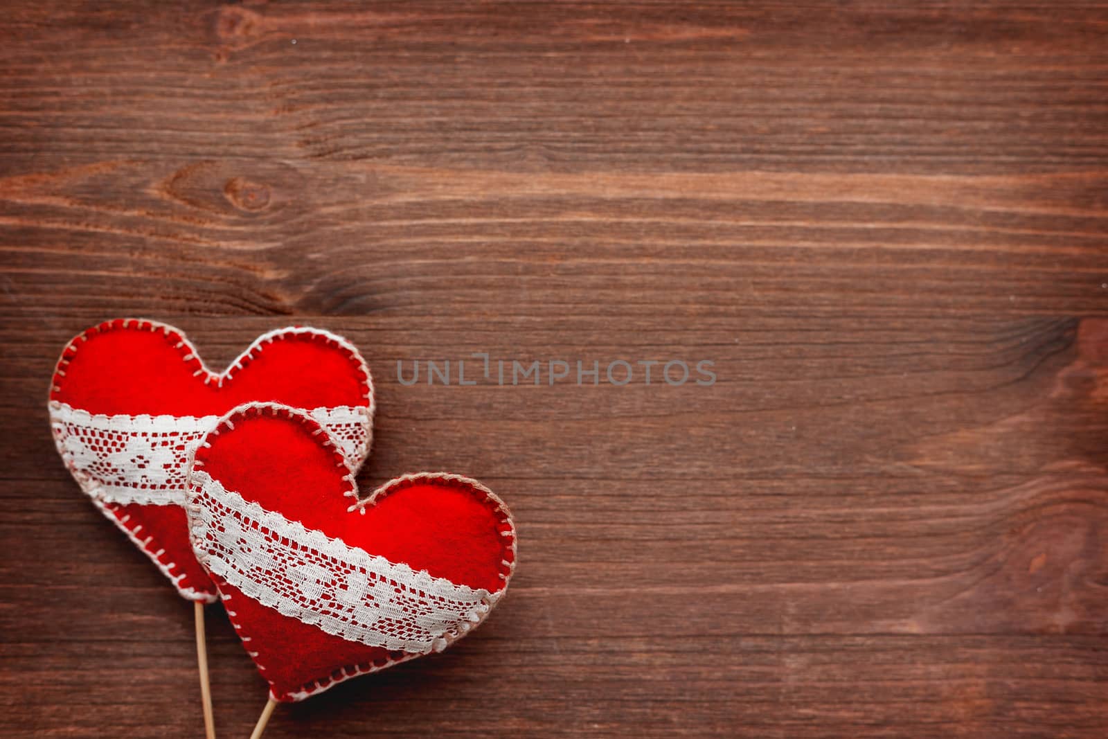 Two felt hearts with laces, symbol of love, on wooden background. Good for Valentine's Day cards. Place for text.