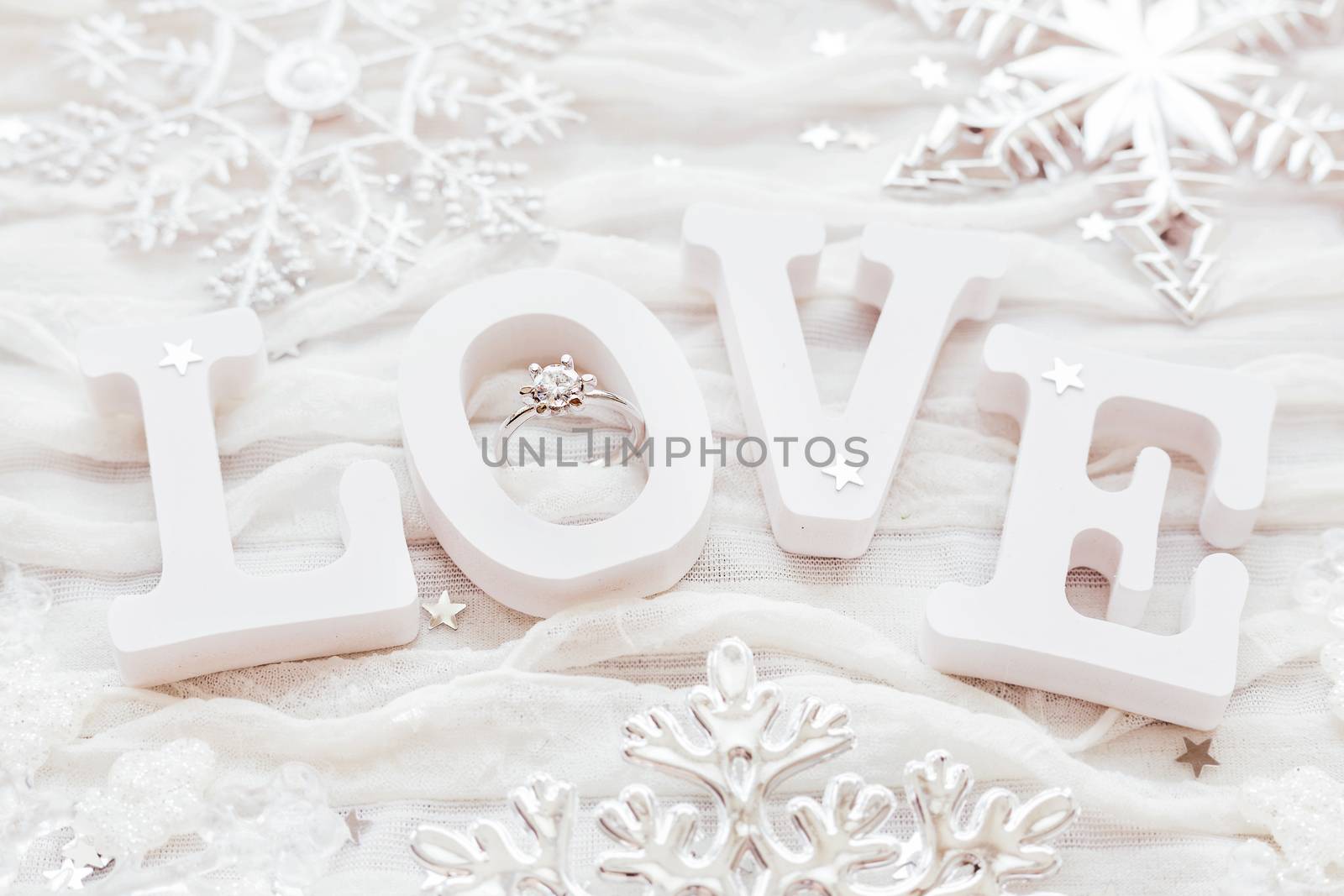 Word LOVE on white fabric background with engagement diamond ring. Good for Valentine's day cards.