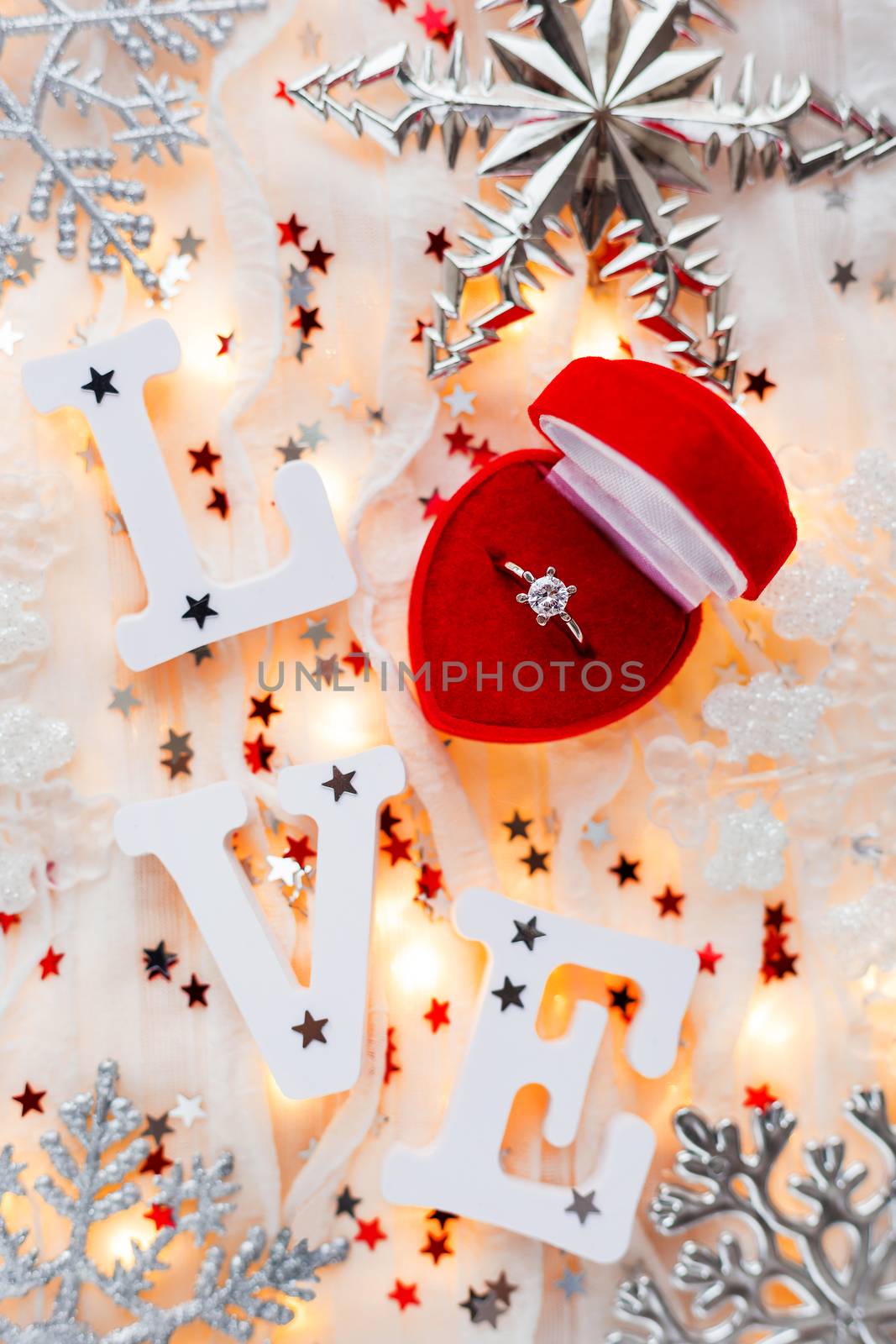 Christmas, New Year and Valentine's Day background with engagement ring, light bulbs and decorations. Symbol of love and marriage.