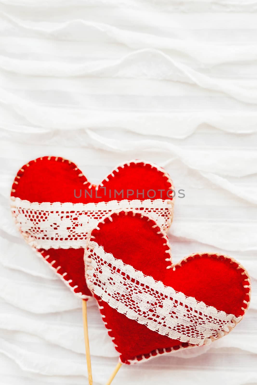 White fabric background with ruche.Two felt hearts with laces, symbol of love. Good for Valentine's Day cards. Place for text.