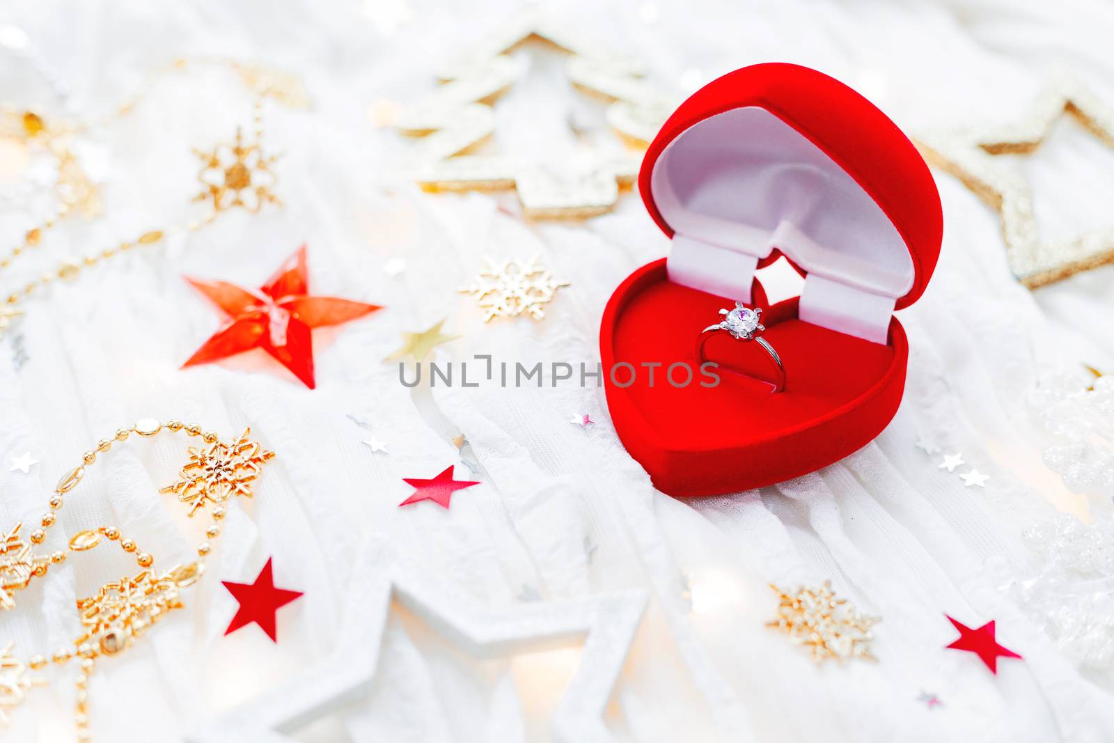 Christmas and New Year holiday background with decorations and engagement golden ring with diamond in gift heart box. Valentine's Day card.