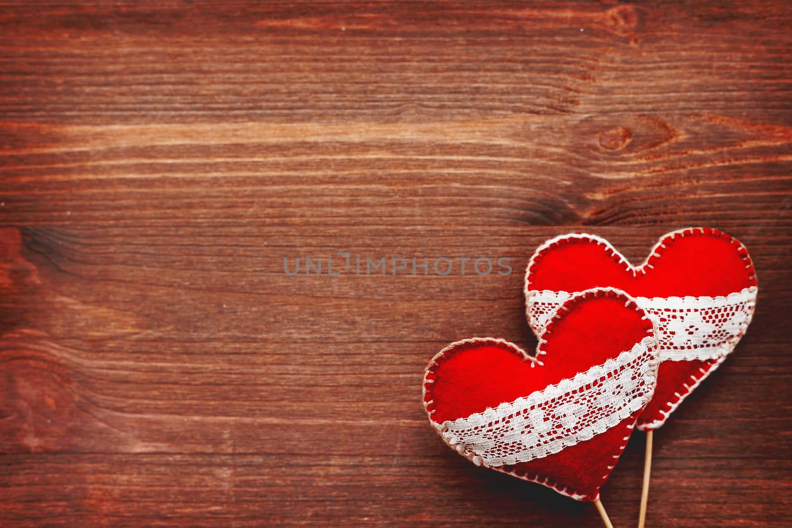 Two felt hearts with laces, symbol of love, on wooden background. Good for Valentine's Day cards. Place for text.