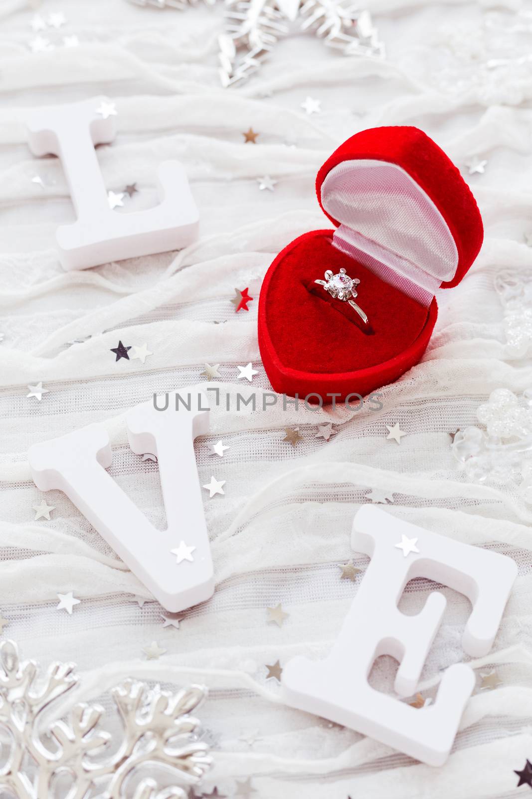 Word LOVE on white fabric background with engagement diamond ring in red gift box. Good for Valentine's day cards.