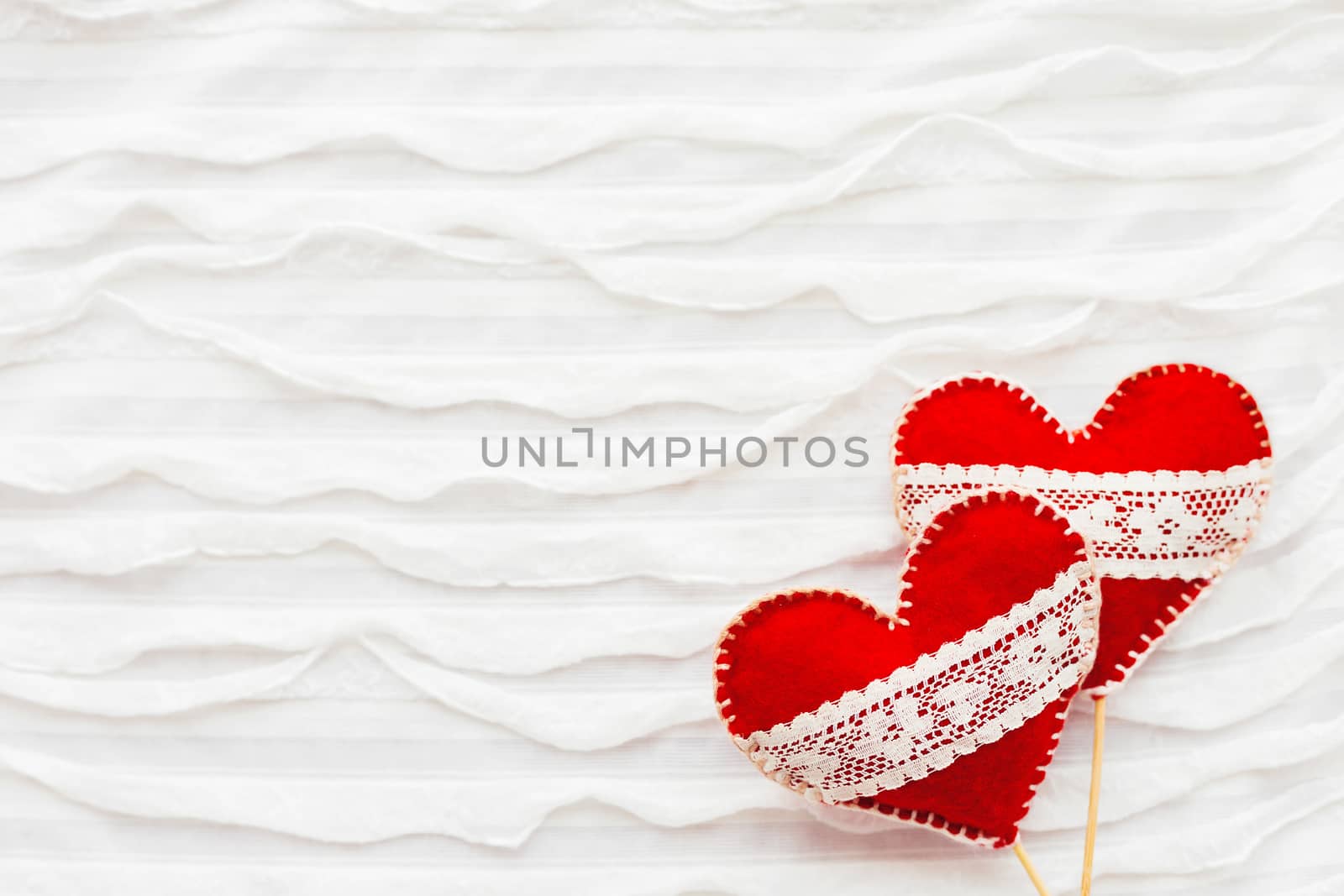 White fabric background with ruche.Two felt hearts with laces, symbol of love. Good for Valentine's Day cards. Place for text.
