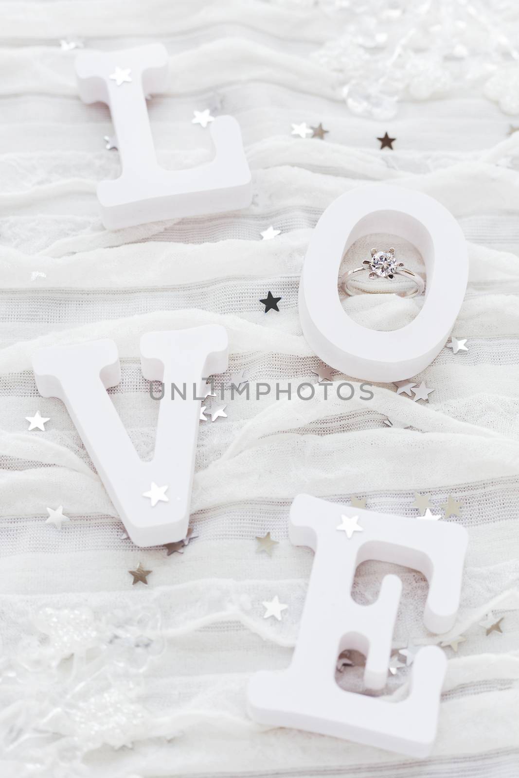 Word LOVE on white fabric background with engagement diamond ring. Good for Valentine's day cards.
