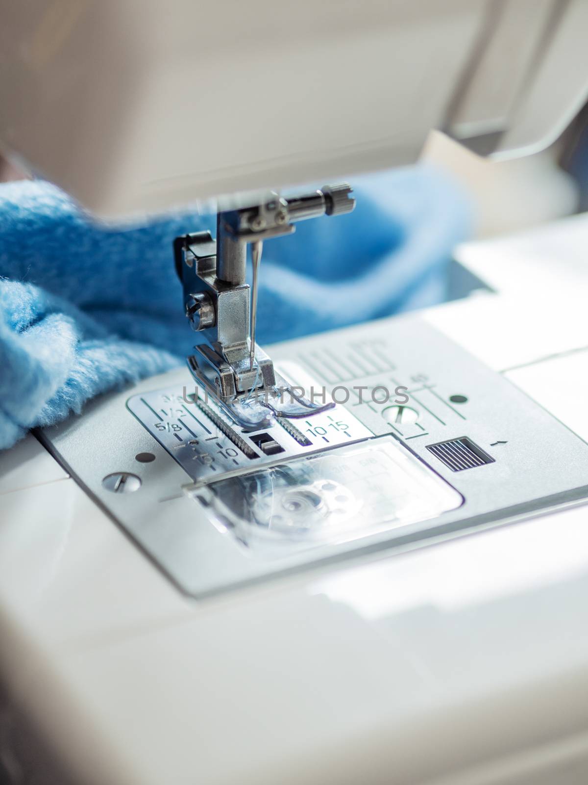 Close up of sewing machine. Blue fabric on background. Equipment for hand made things, hobby.