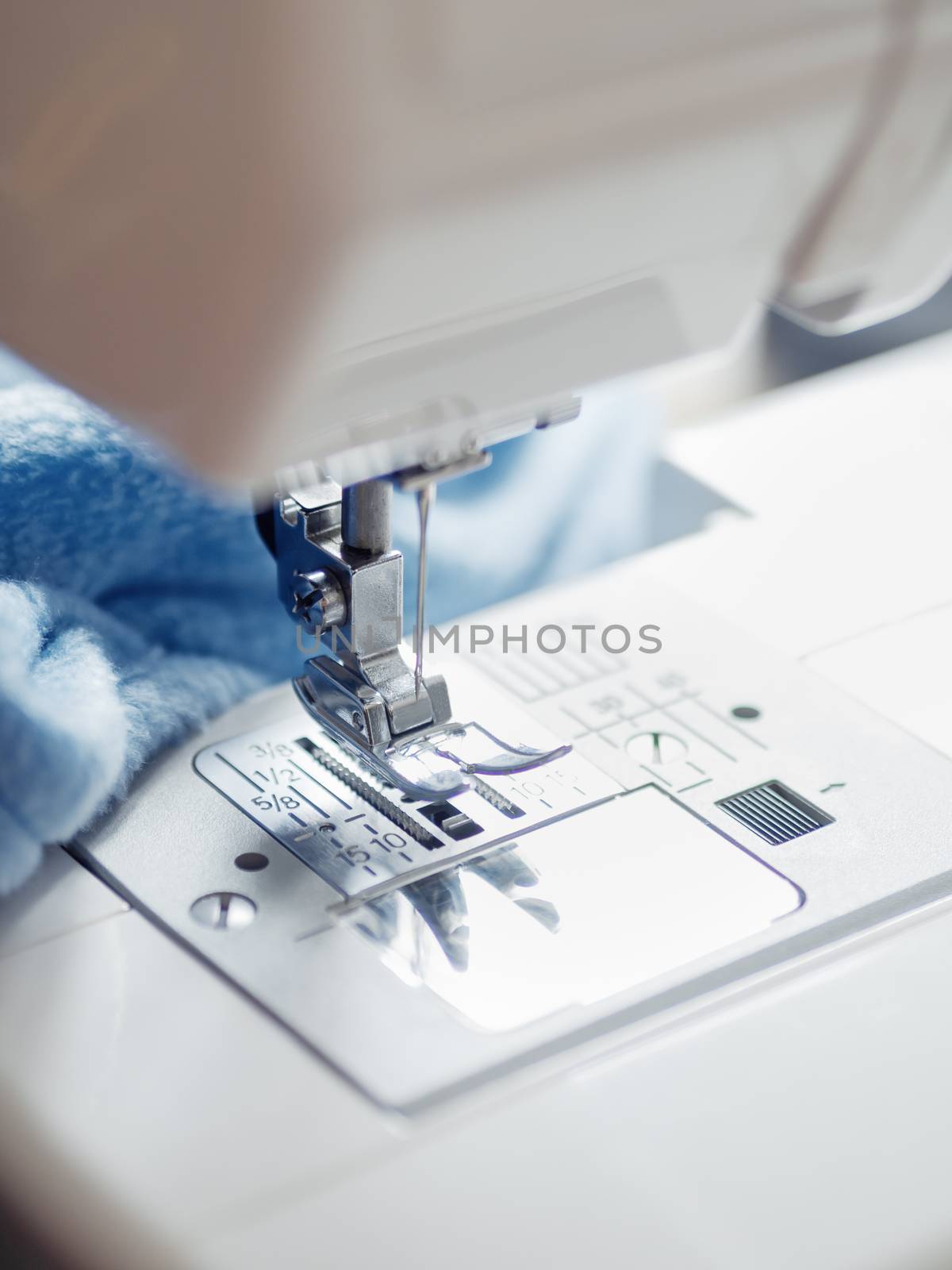 Close up of sewing machine. Blue fabric on background. Equipment for hand made things, hobby.