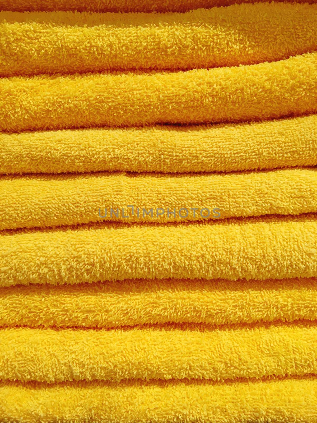 Stack of yellow terry towels. Pile of textile bath accessories.