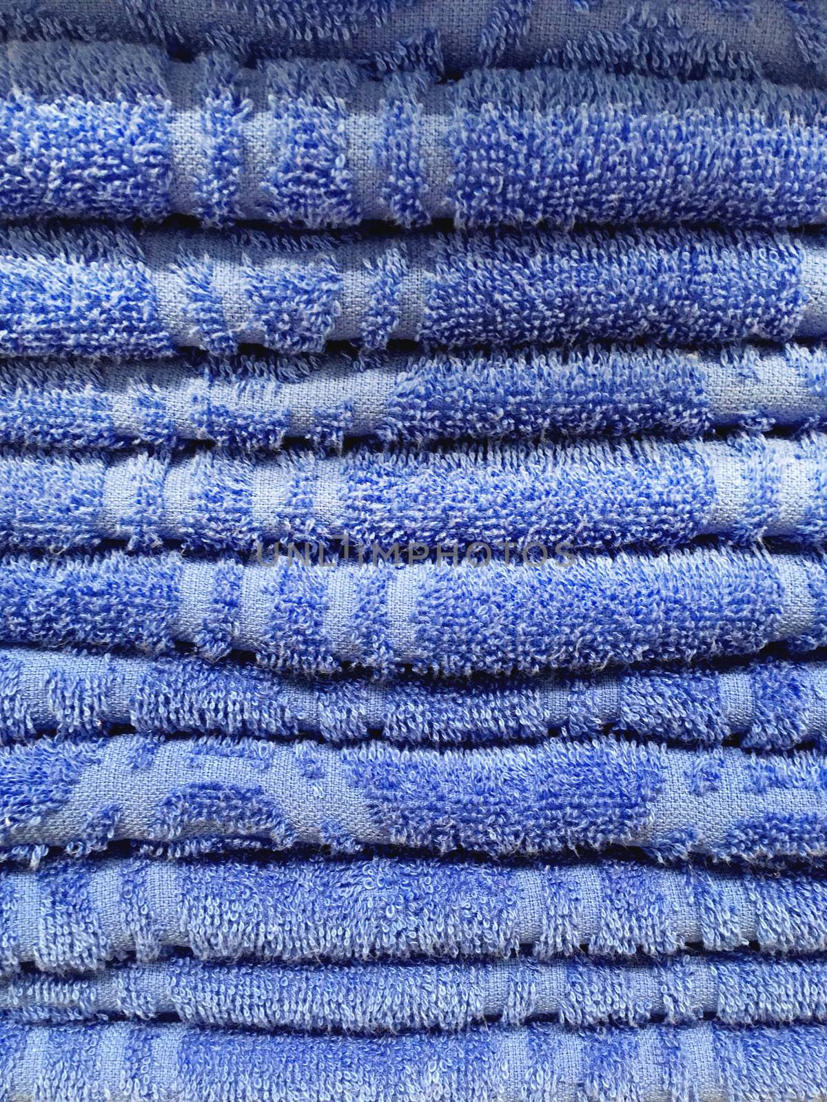 Stack of blue terry towels. Pile of textile bath accessories.